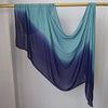 Pañuelo hijab degradado fluído en tonos azules y verde azulado colgado en una varilla de madera.