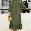 Une femme portant une robe maxi bohème vert olive à volants, debout sur un chemin de pierre.