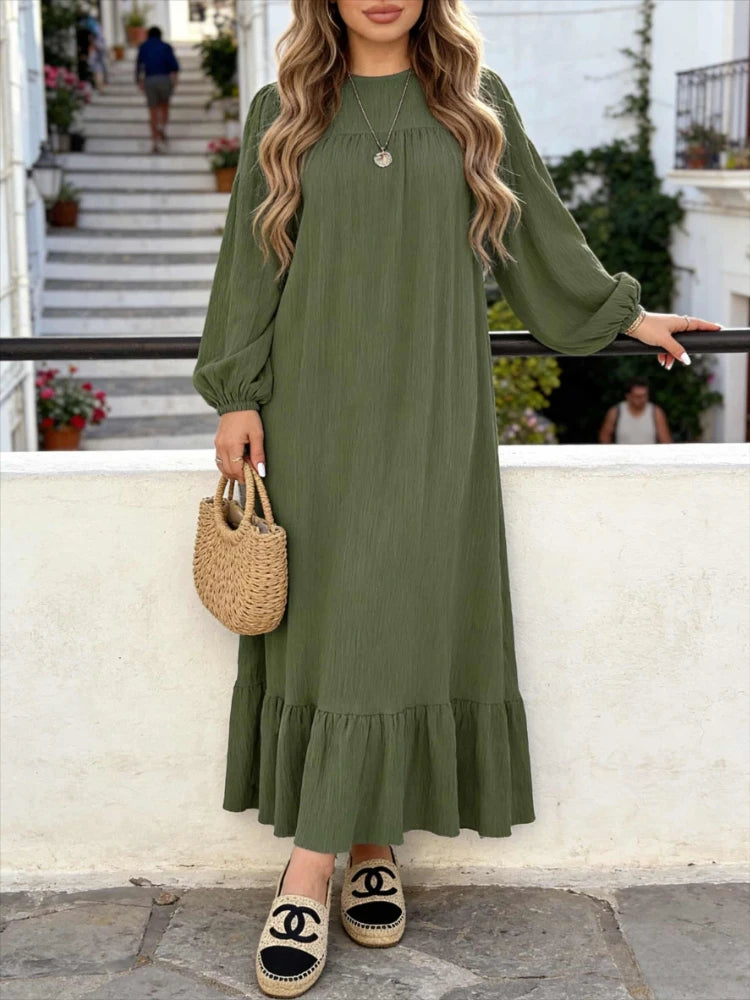 Une femme portant une robe maxi bohème vert olive à volants, debout sur un chemin de pierre.