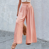 Un mannequin portant un pantalon large rose pâle à taille élastique et détails en dentelle, associé à un haut blanc.