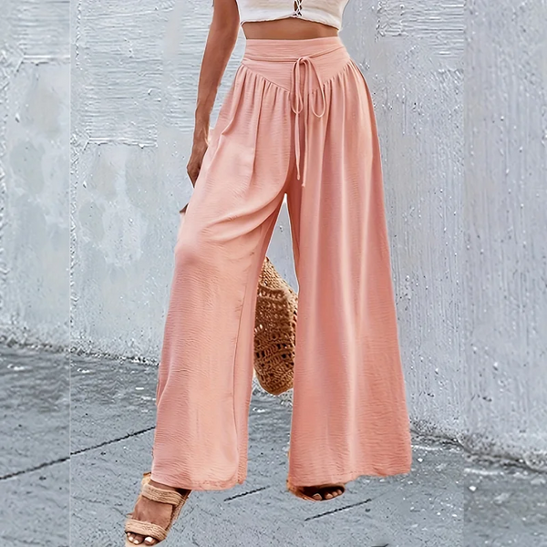 A model wearing light pink wide-leg pants with an elastic waist and lace detail, paired with a white top.