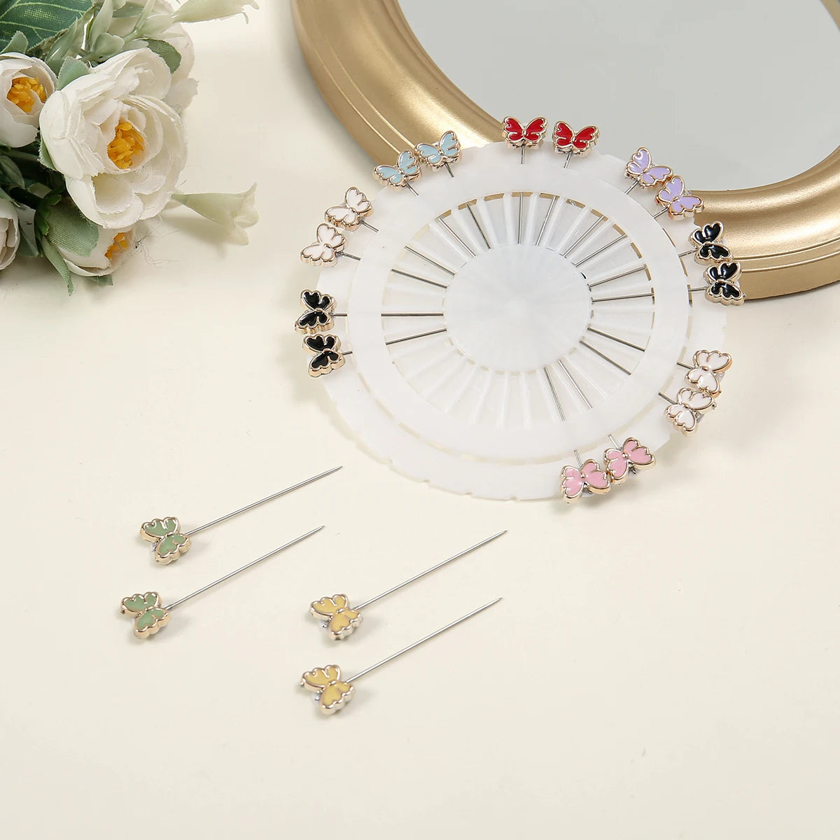 Un set de alfileres para hijab de seda con diversos patrones de mariposas en rosa, dorado y negro sobre una base circular bla