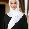 Une femme portant un foulard instant blanc sur un haut noir.