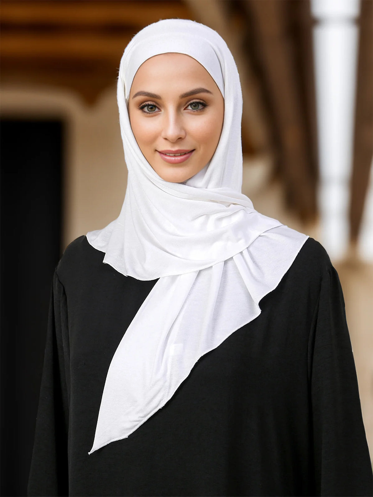 Une femme portant un foulard instant blanc sur un haut noir.