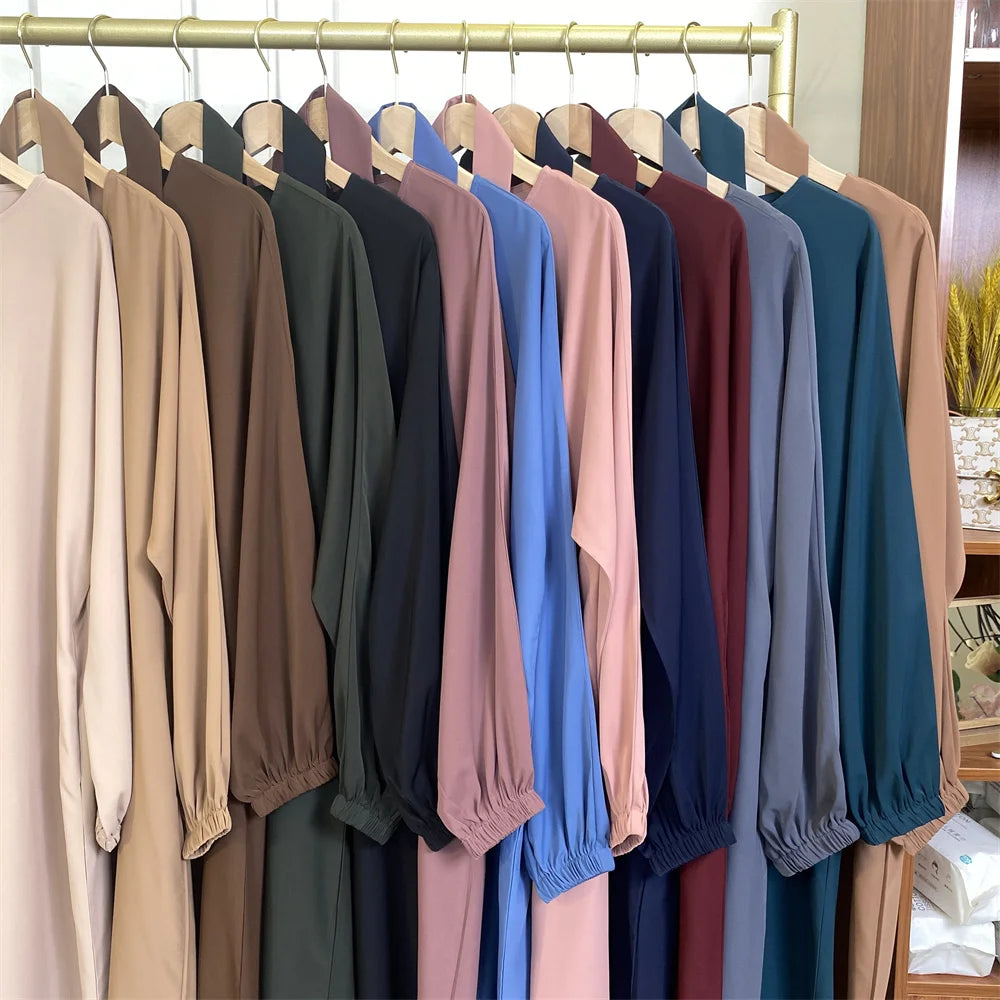 Regal mit Frauen-Kaftanen in marokkanischem Stil in verschiedenen Beigetönen, Braun, Olivgrün und Blau, an einem Holzstamm au