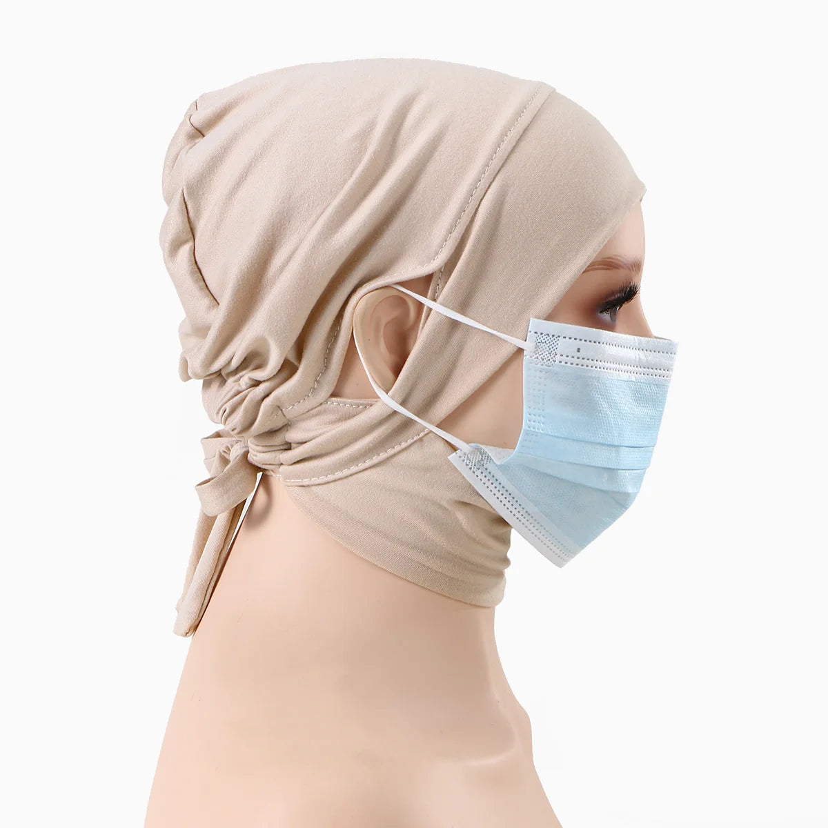 Eine Frau trägt eine beige Jersey-Baumwoll-Hijabkappe und eine hellblaue Gesichtsmaske.