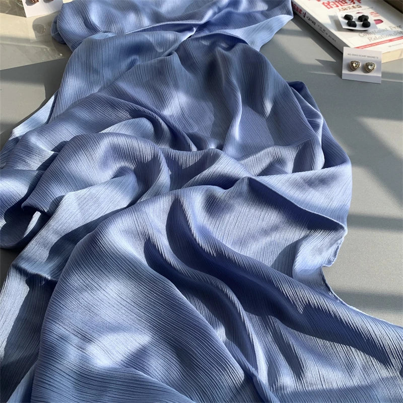 Fallendes hellblaues Crinkle-Satin-Chiffon-Hijab-Stoff mit Falten und Textur.