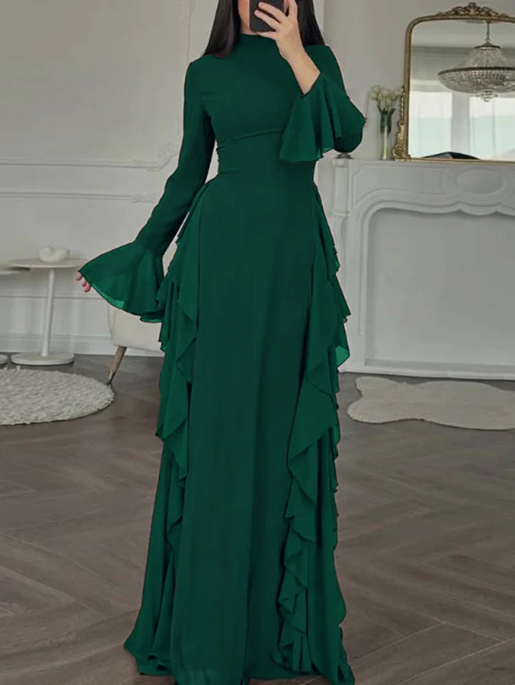 A full-length emerald green maxi dress with a high neckline and ruffled sleeves displayed indoors.