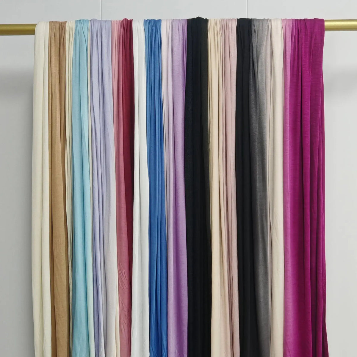 Exhibición de pañuelos de hijab de algodón degradados doble cara en varios tonos como beige, azul, rosa, morado y negro.