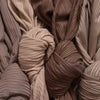 A close-up of multiple rolled ribbed jersey hijab scarves in various shades of beige and brown.