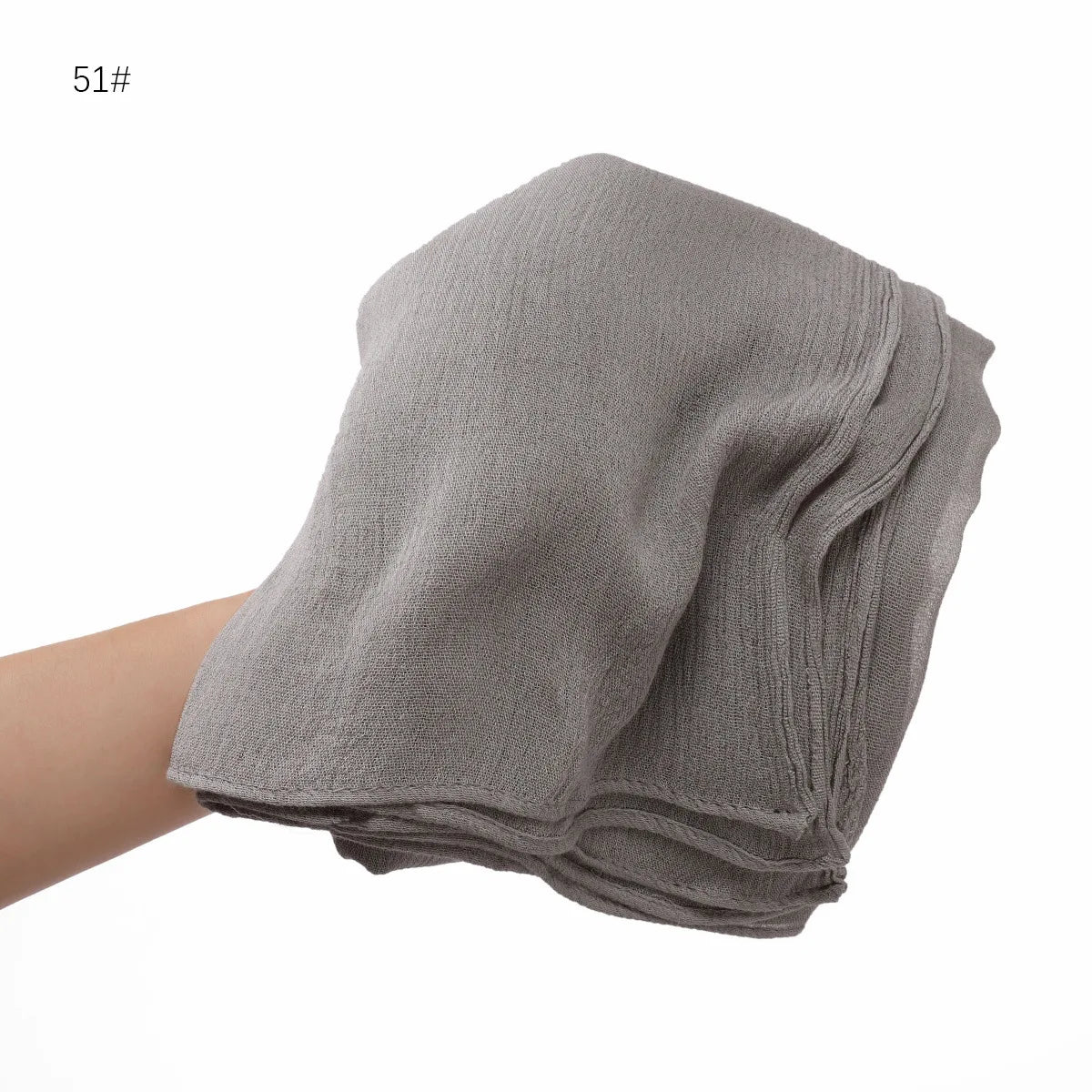 Écharpe châle en crinkle gris drapée sur une main.