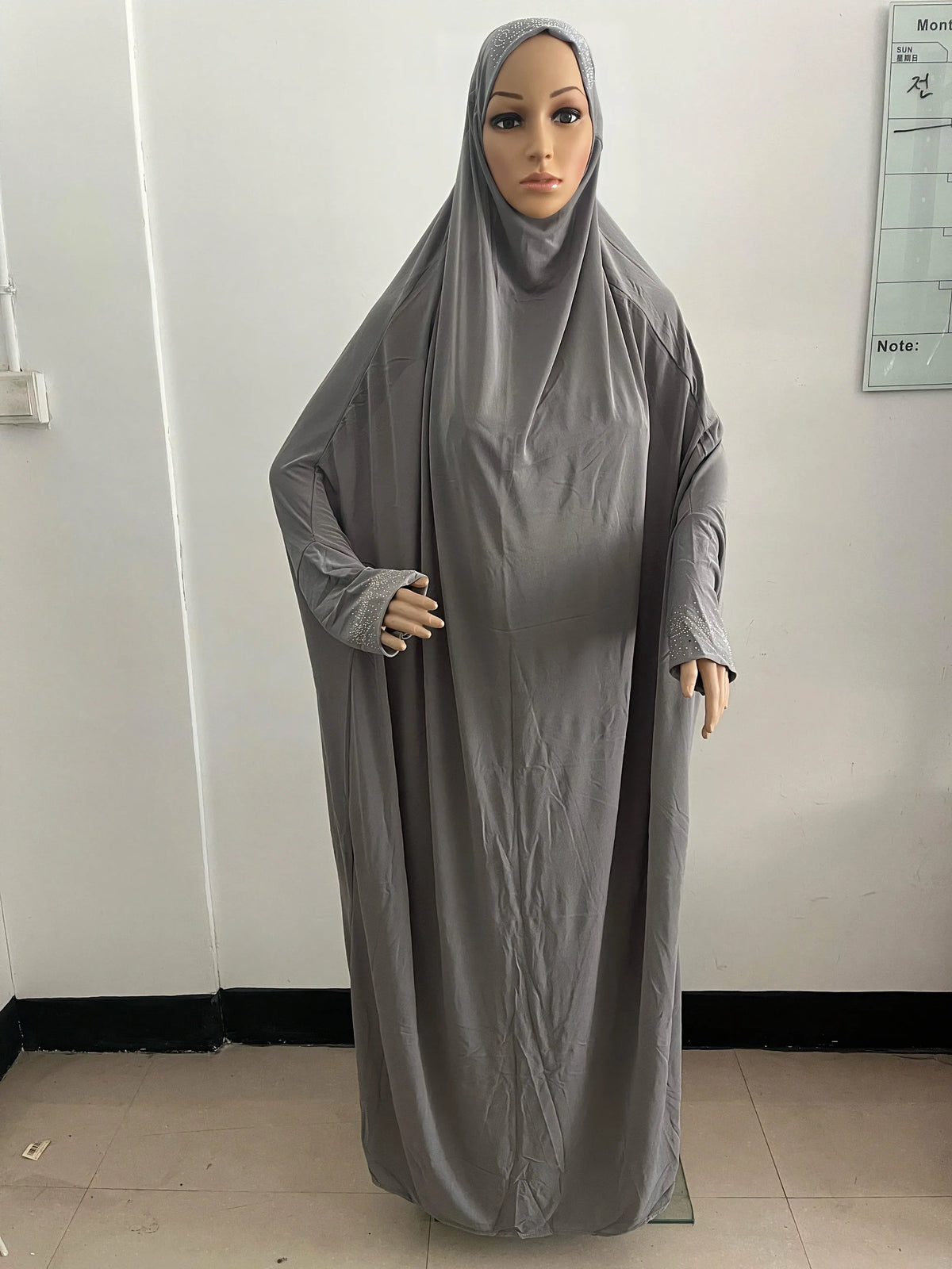 Une longue caftan abaya grise et fluide présentée sur un mannequin.