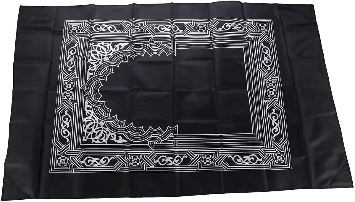 Black fabric prayer rug with an ornate white geometric border design.