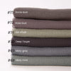 Pile d'échantillons de tissu gris et de couleurs sourdes, étiquetés #73 à #68 pour un foulard hijab.