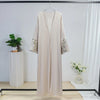 Beige bestickte, weite Kaftan-Abaya an einem Haken vor weißem Hintergrund.