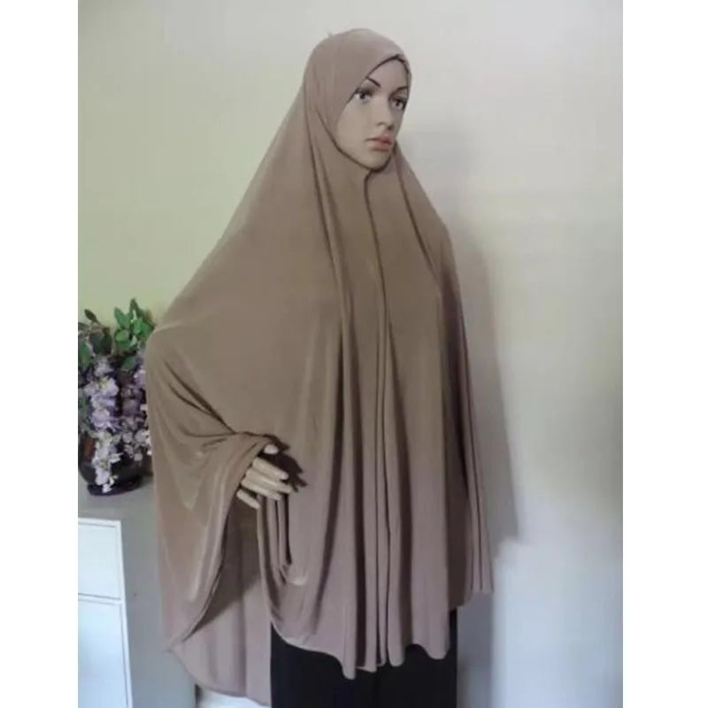 Una mujer vistiendo un pañuelo tipo jersey beige oversize, en un retrato de cuerpo completo.