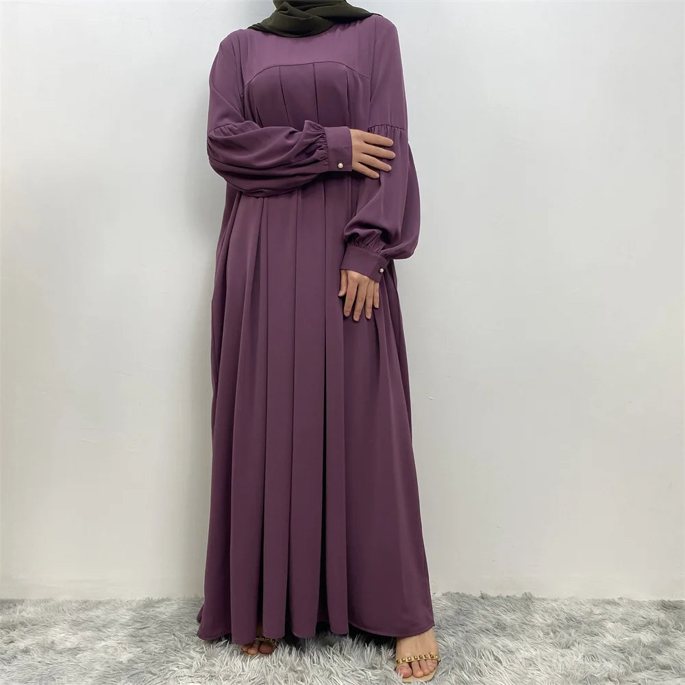 Eine Frau trägt ein elegantes langes lila islamisches Kleid und einen grünen Hijab.