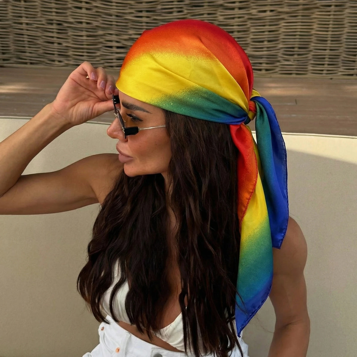 A woman wearing a colorful rainbow silk scarf tied around her hair and neck.