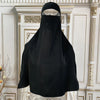 Schwarze elegante Maxi-Abaya auf einem Mannequin vor einem goldenen, verzierten Hintergrund
