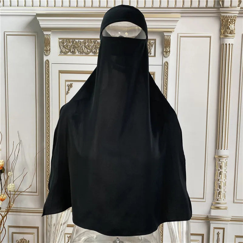 Schwarze elegante Maxi-Abaya auf einem Mannequin vor einem goldenen, verzierten Hintergrund