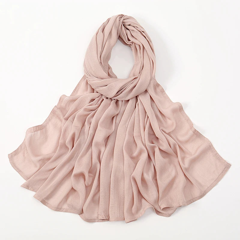 Pañuelo pashmina de algodón rayón color rosa suave, drapeado alrededor del cuello.