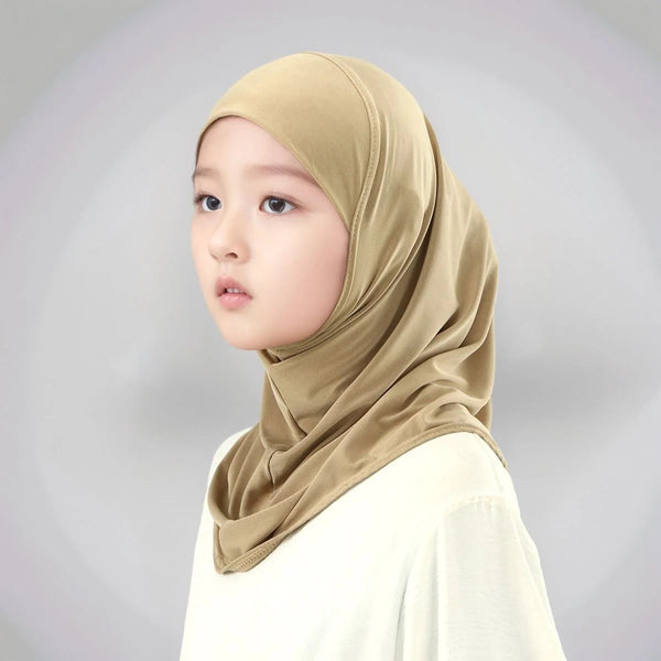 A young girl wearing a beige instant cotton modal hijab head wrap and a white top.