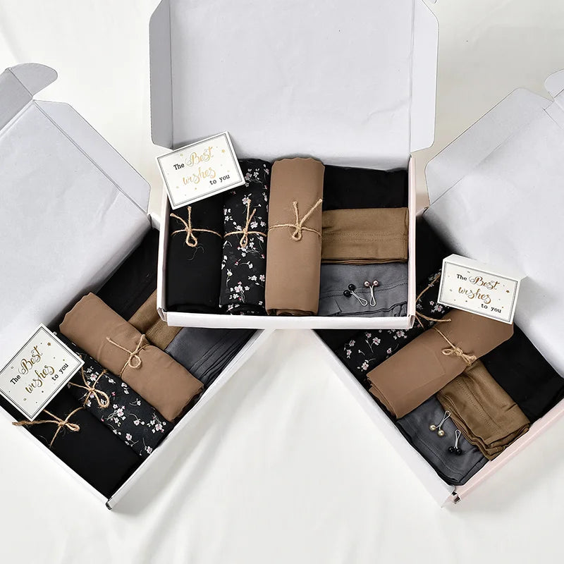 Un ensemble de foulards hijab en mousseline de coton élégants dans diverses tons terre et noirs, emballés dans une boîte blan