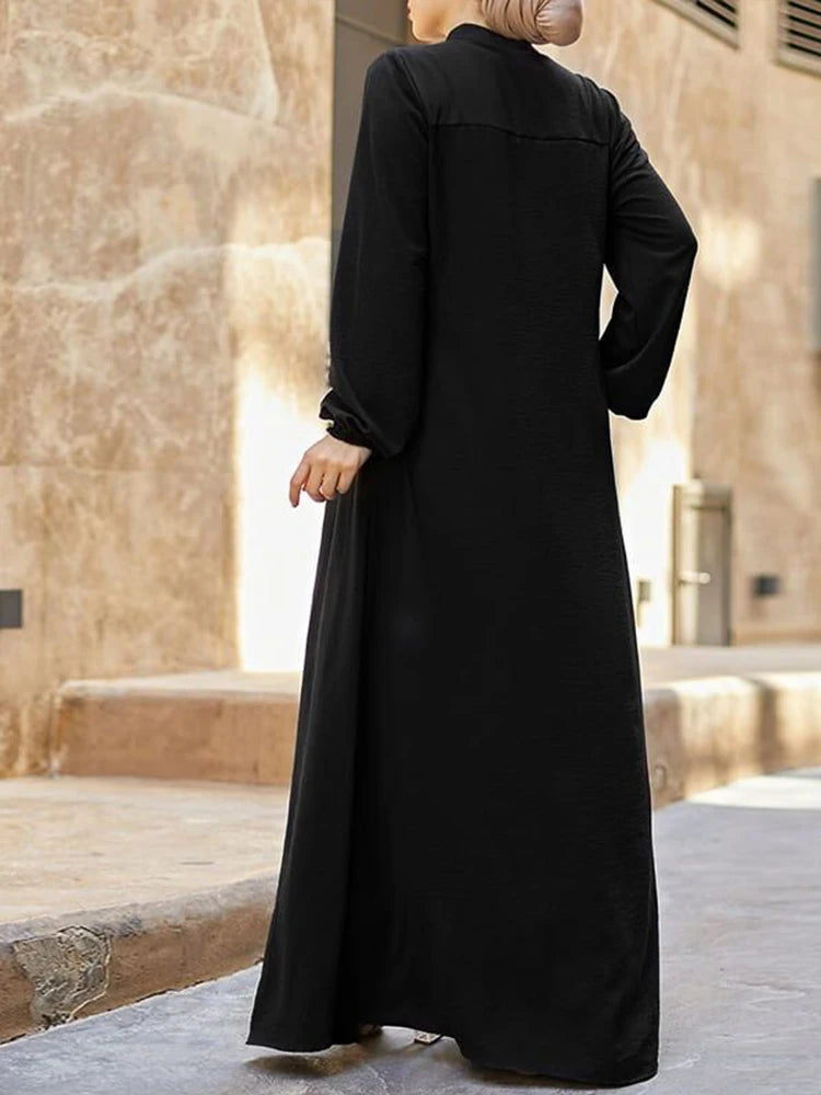Femme portant une élégante robe longue noire ample avec col montant, vue de dos.