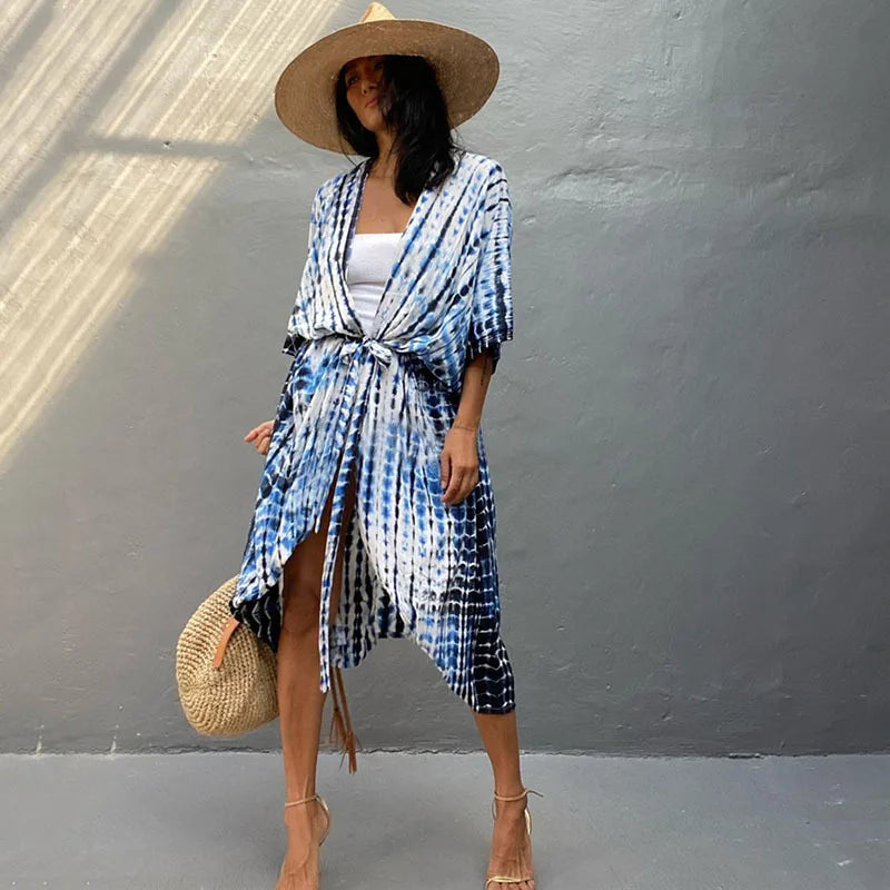 Eine Frau trägt ein blau-weiß gemustertes Sommer-Strandkimono-Kleid mit breiter Strohhut.