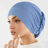 Eine Frau trägt eine hellblaue Stretch-Turbanmütze auf dem Kopf.
