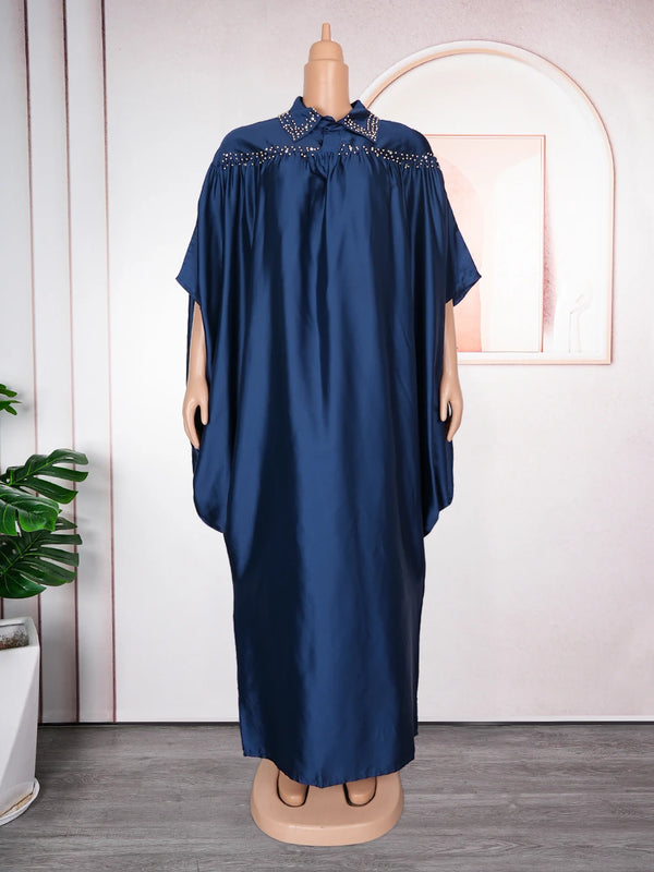 A navy blue luxury African kaftan abaya displayed on a mannequin against a light pink wall.