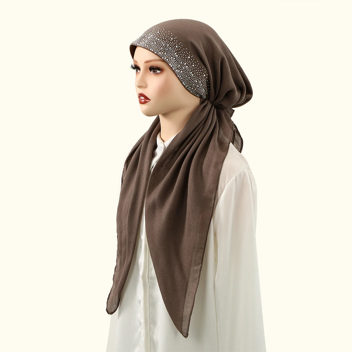 Eine Frau trägt eine braune Stoff-Haube mit silbernen Steinchen und ein weißes Oberteil.