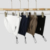 A display of four adjustable modal hijab caps in white, navy blue, olive green, and black hanging from a wooden rack.