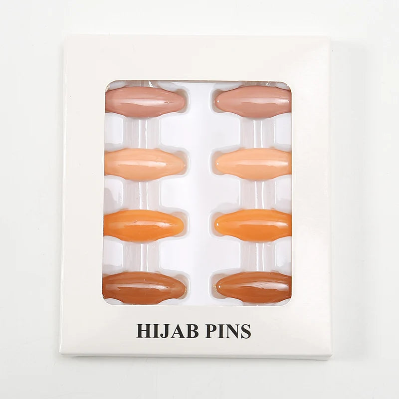 Un juego de ocho sujetadores y pinzas de hijab beige y naranja, exhibidos en una caja rectangular blanca.