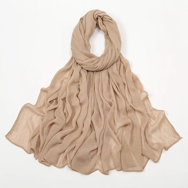 Écharpe/foulard crinkle beige drapé autour du cou et tombant sur les épaules.