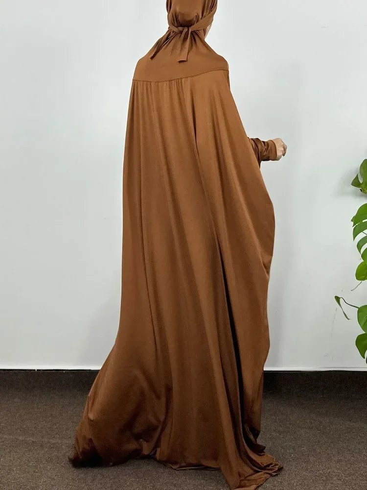 Una abaya marrón elegante de largo completo con capucha, drapeada sobre una persona contra un fondo blanco.
