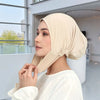 Eine Frau trägt eine beige weiche Baumwoll-Seiden-Innenschleierkappe in einem hellen Innenraum.