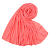 Un foulard en jersey de coton rose corail vibrant, roulé et drapé, montrant sa texture douce.