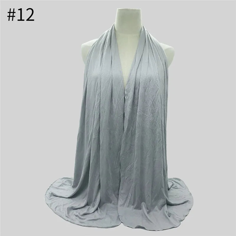 Heller grauer Baumwolljersey-Hijabschal, drapiert auf einem Mannequin.