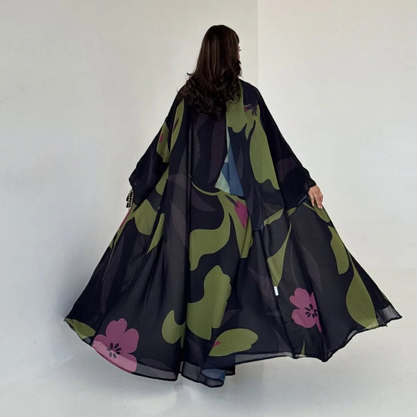 A woman wearing a black and olive green chiffon abaya set with floral patterns, viewed from the back.
