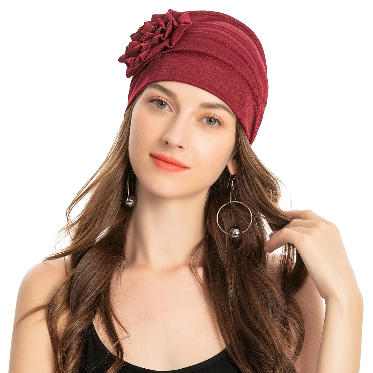 Eine Frau trägt eine tiefrote, florale bestickte Hijab-Turbanmütze mit langen braunen Haaren.