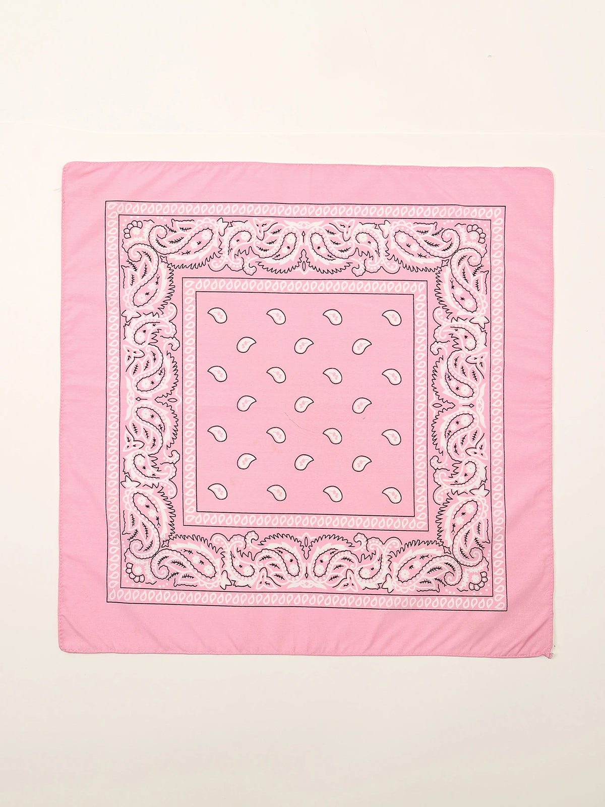 Tissu rose avec une bordure paisley blanche détaillée et un motif de petites formes blanches.
