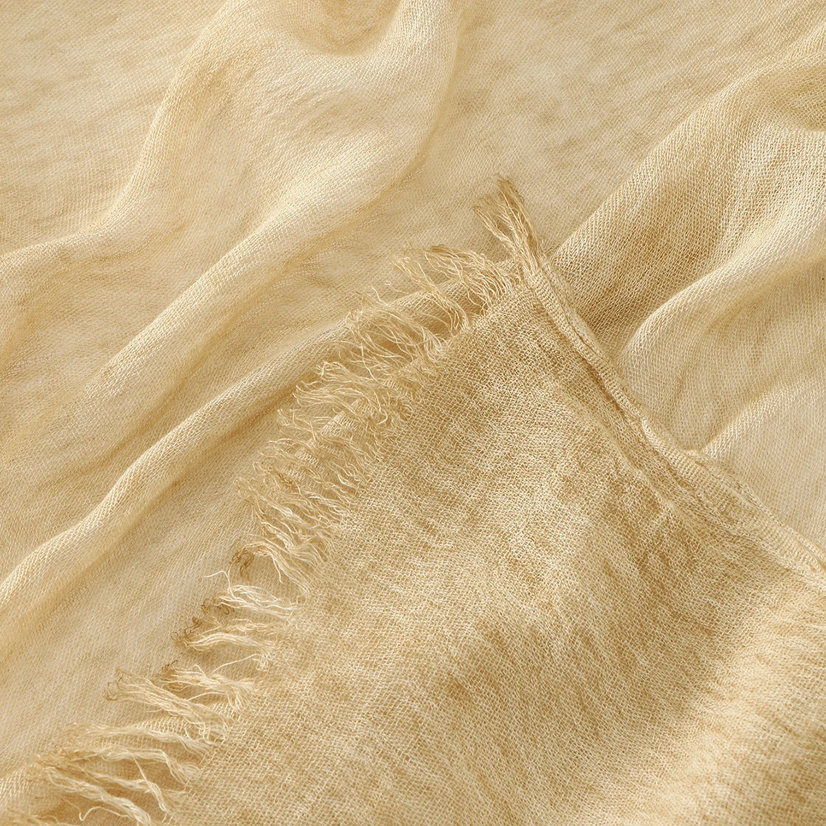 Gros plan d'un foulard hijab en rayon crinklé beige avec des bords effilochés.