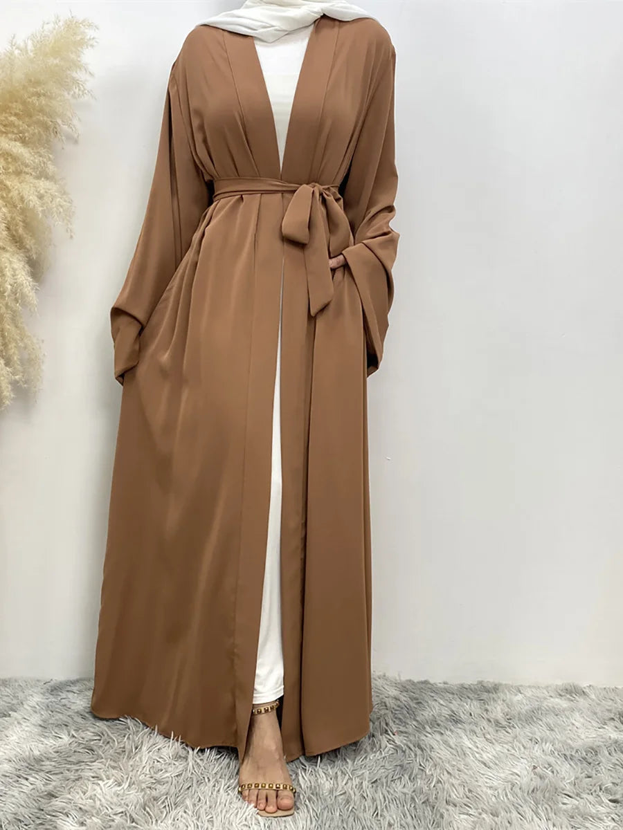 Braune, fließende Abaya-Kaftan mit offenem Vorderteil über einem weißen Top, vor hellem Hintergrund.