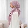 Una mujer vistiendo un hiyab color rosa empolvado con una diadema elástica de diamantes y una blusa blanca.