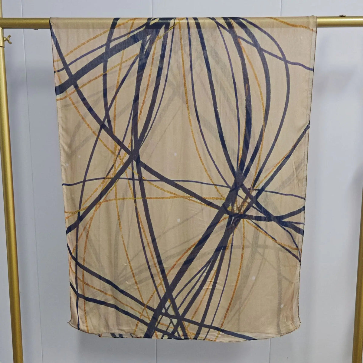Helles beige Schal mit dunklen blau-goldenen abstrakten Linien, aufgehängt.