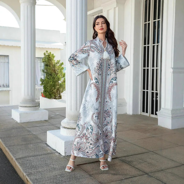 A woman wearing an elegant diamond beaded long abaya dress standing in a white colonial-style courtyard.