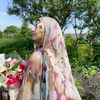 Una mujer usando un pañuelo hijab con estampado de leopardo acuarela bohemio al aire libre.