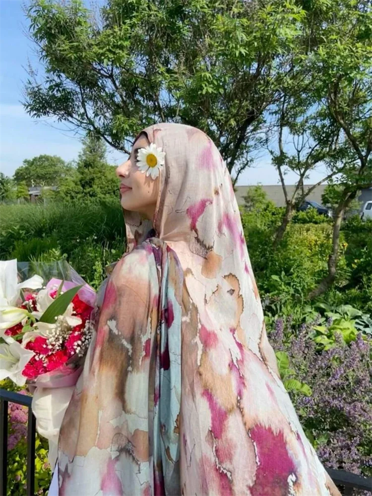 Una mujer usando un pañuelo hijab con estampado de leopardo acuarela bohemio al aire libre.