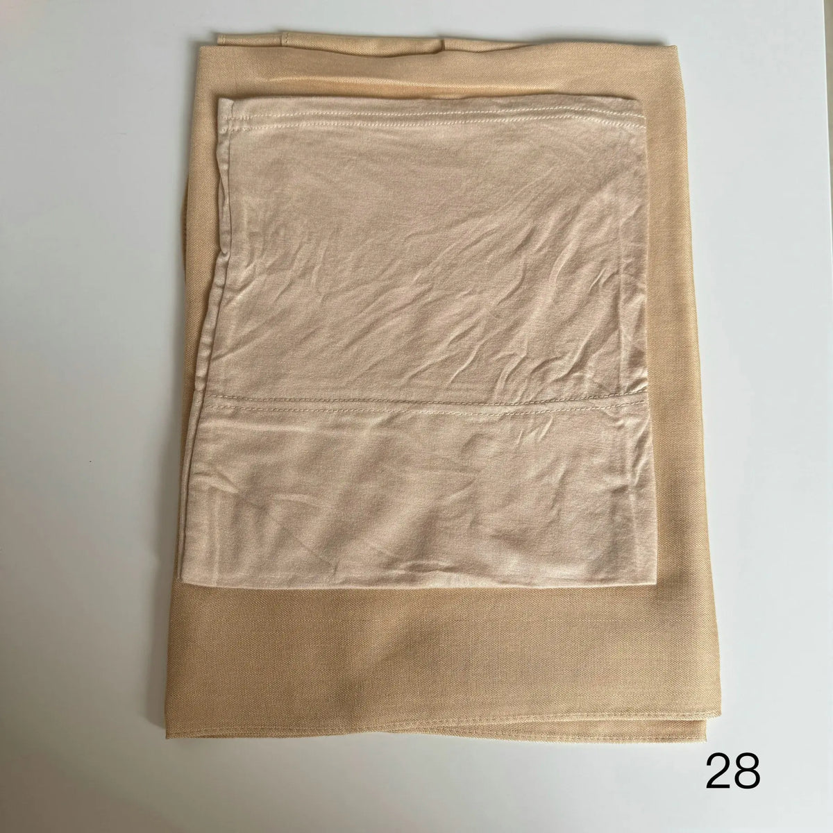 A beige soft modal rayon hijab set folded and displayed on a white surface.
